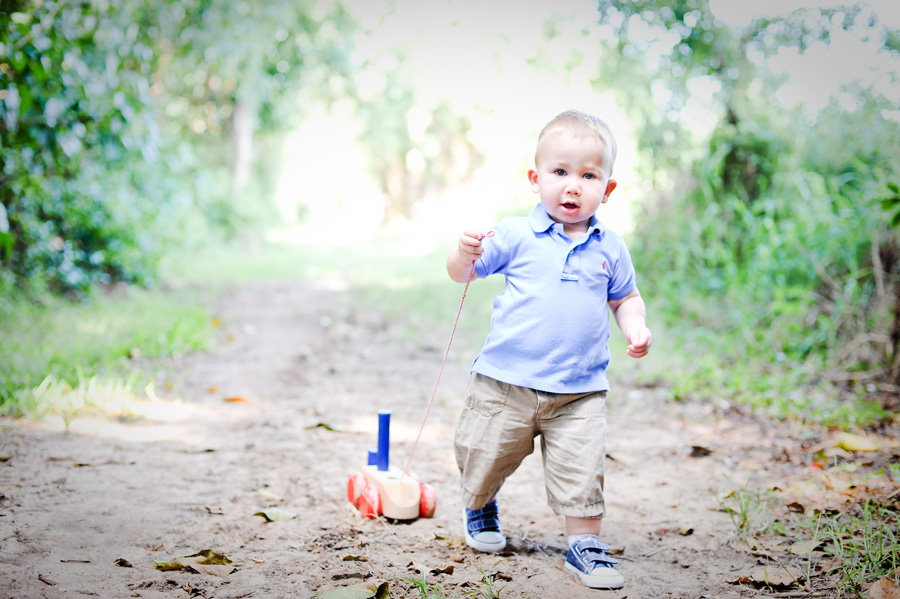 Little boy walking with play toy in park.