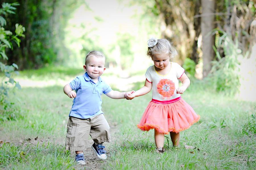 Brother and sister walking through field.