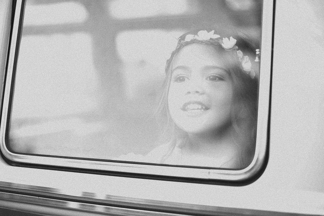 Child looks out the window of a vintage VW Bus.